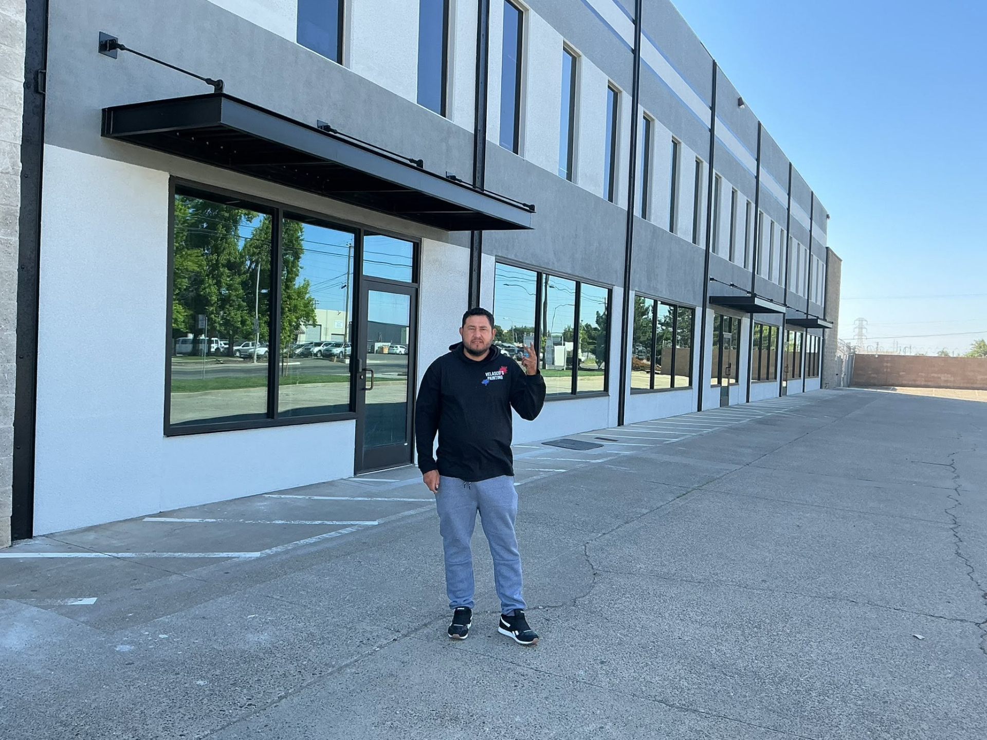 Velasco standing in front of a freshly repainted long commercial facade