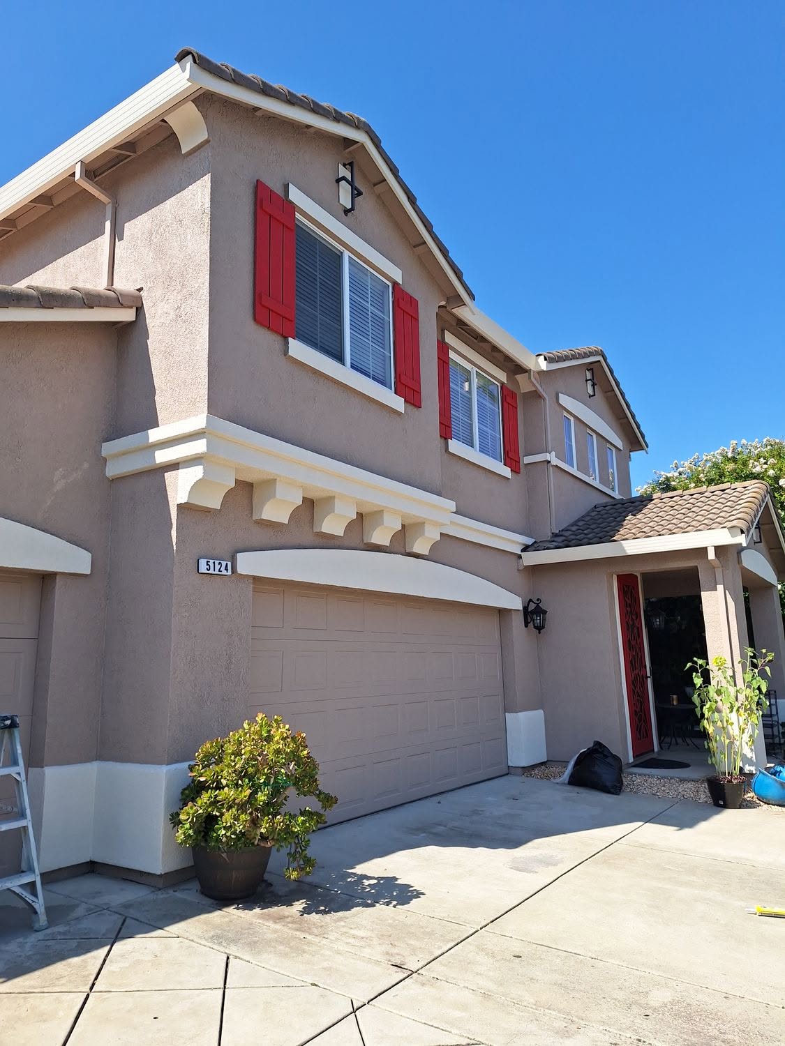 Warm stucco two-story with fresh red shutters and door