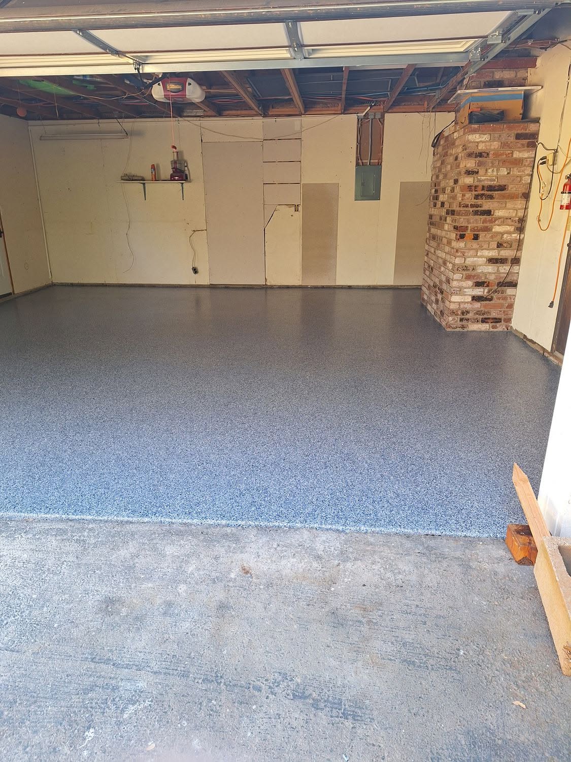 Blue speckle epoxy garage floor with brick accent wall