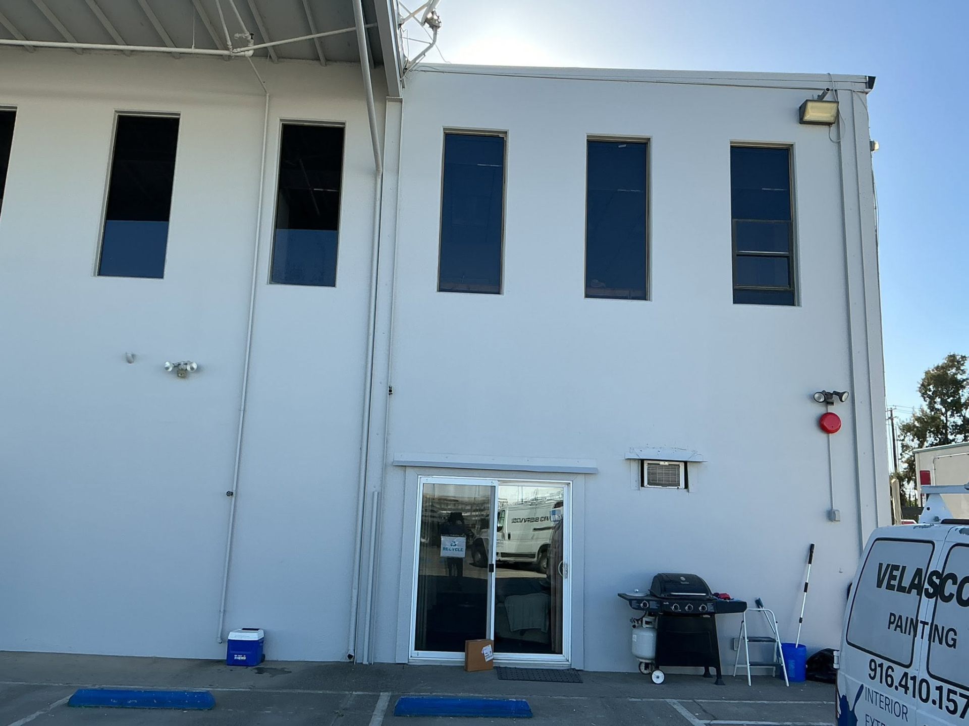 White commercial warehouse rear elevation with Velasco's Painting van on site