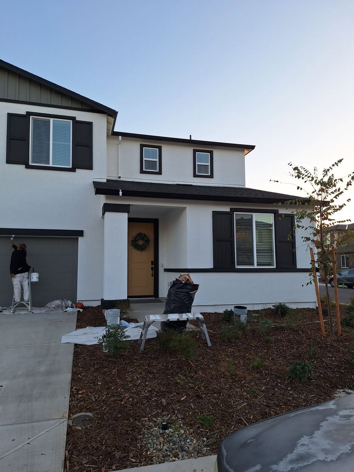 Painter on ladder working on two-story exterior repaint