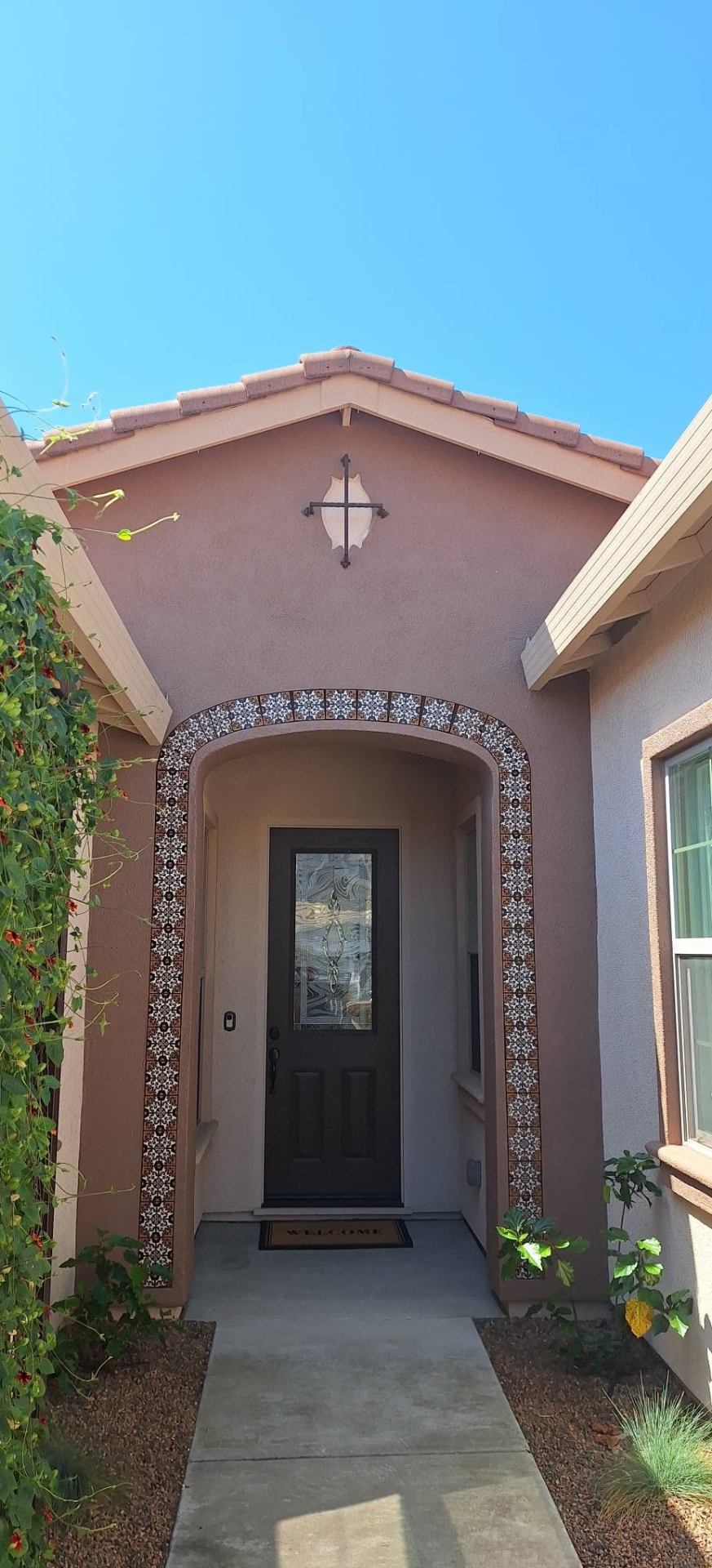 Spanish-style entry with mauve stucco and decorative tile arch