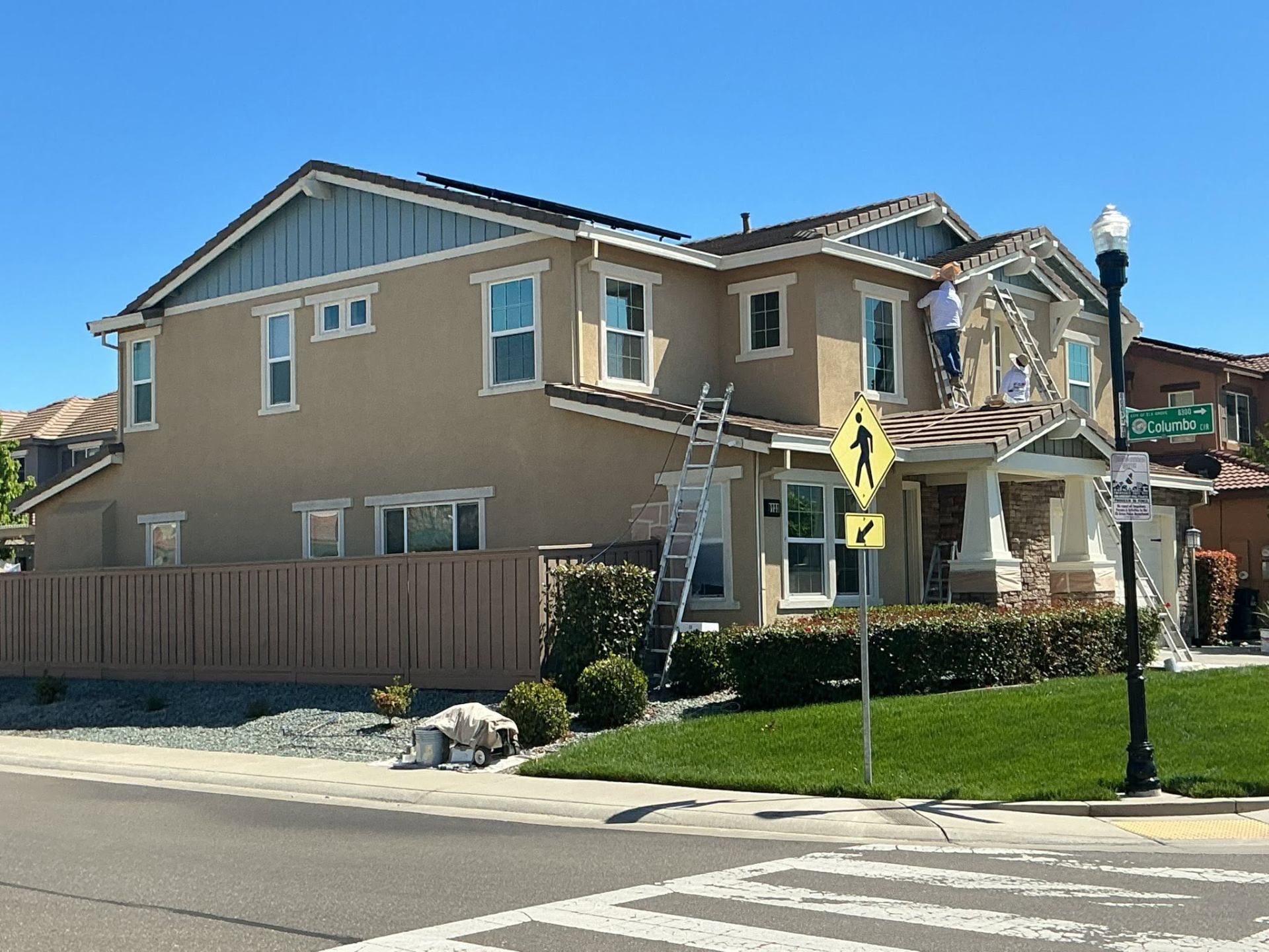 Velasco's crew painting a tan and blue craftsman corner-lot home